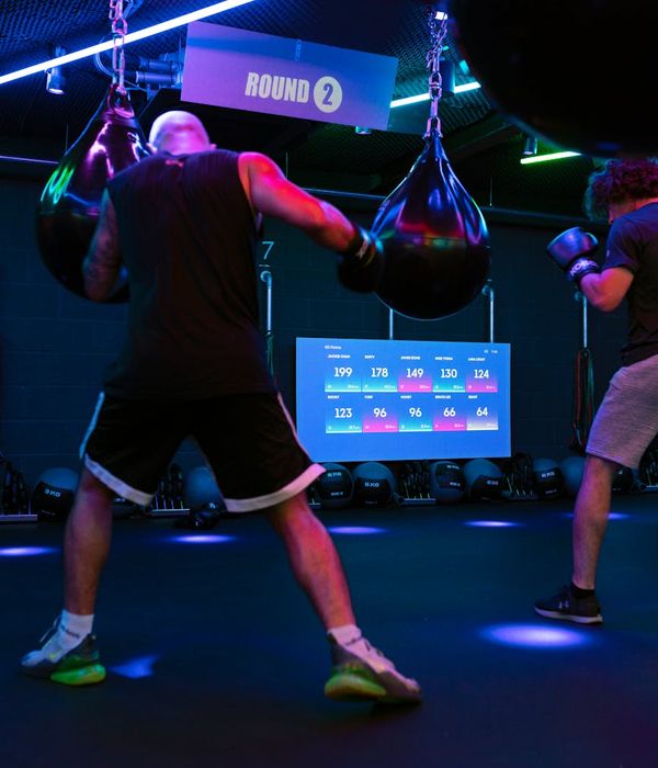 Man performing a strength exercise in a modern, dark gym environment.